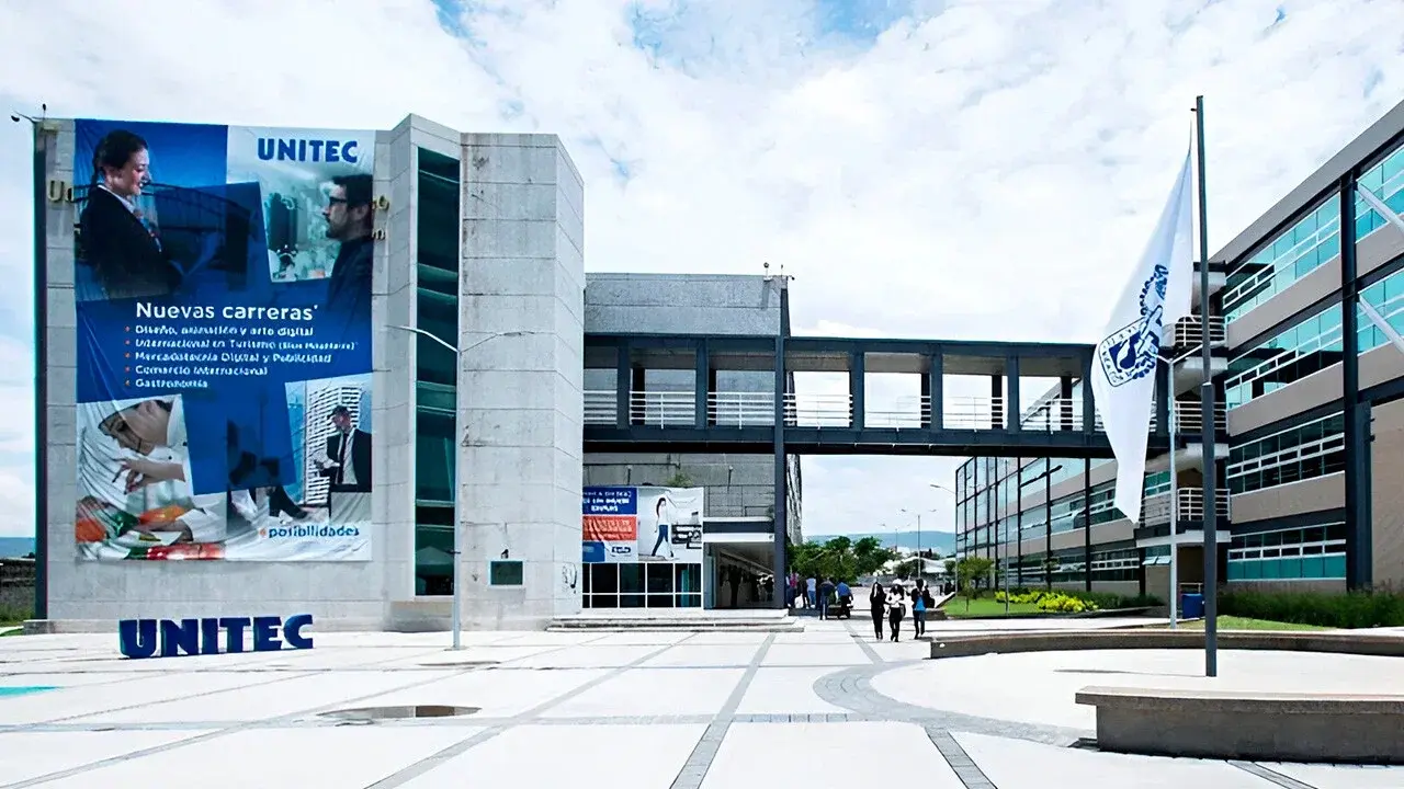 Edificio de la UNITEC, mostrando su fachada y una pasarela, recibe estudiantes en un campus amplio y soleado.