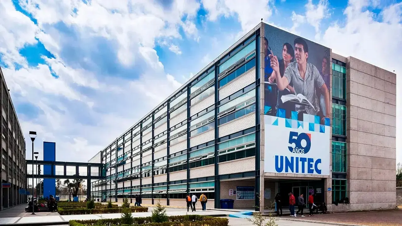 Edificios de la UNITEC se alzan, mostrando un pasillo central con jardinería; un anuncio de 50 años UNITEC destaca en uno.