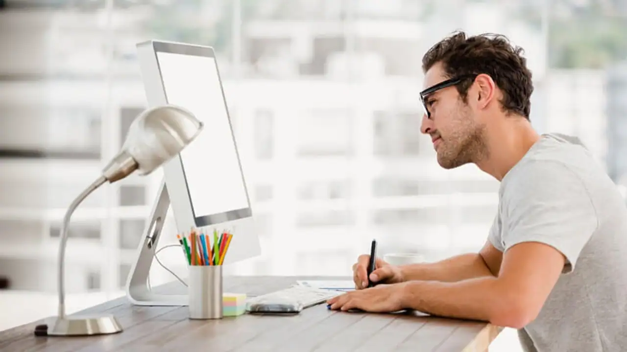 Estudiante de la carrera en diseño gráfico realizando trabajos en su mac de escritorio