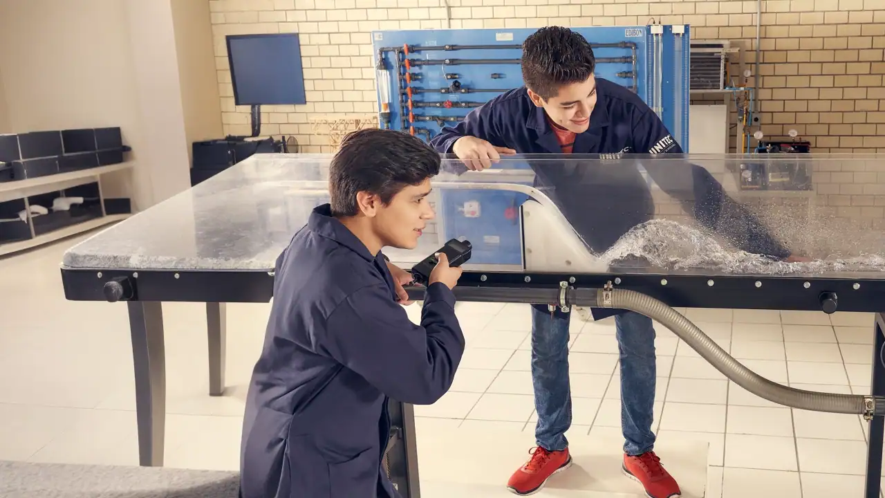 Estudiantes de ing en obras civiles realizando un experimento relacionado con la mecánica de fluidos o hidráulica, utilizando un equipo que simula el flujo de agua.