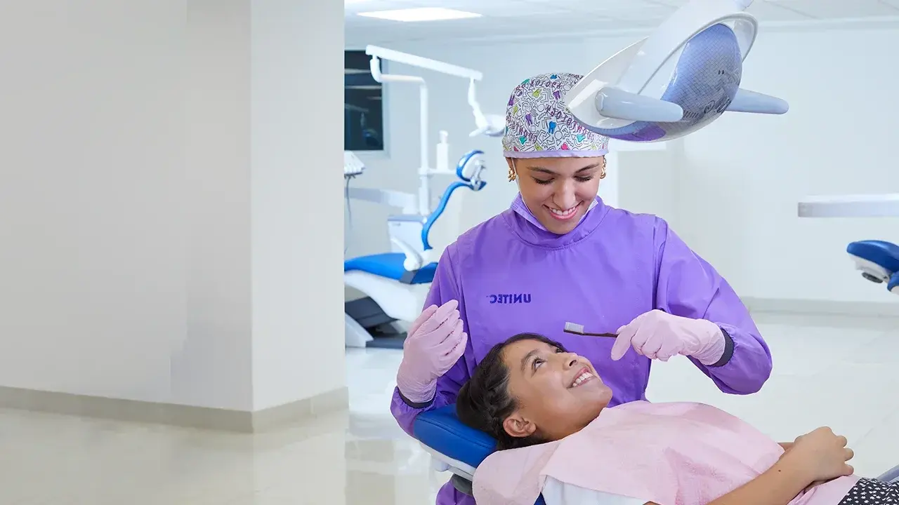 Egresada de la lic en odontología UNITEC atendiendo a paciente infante en consultorio dental