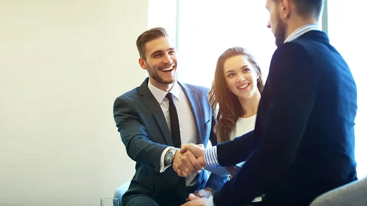 Tres profesionales de la carrera en negocios internacionales colaboran en una reunión de trabajo.