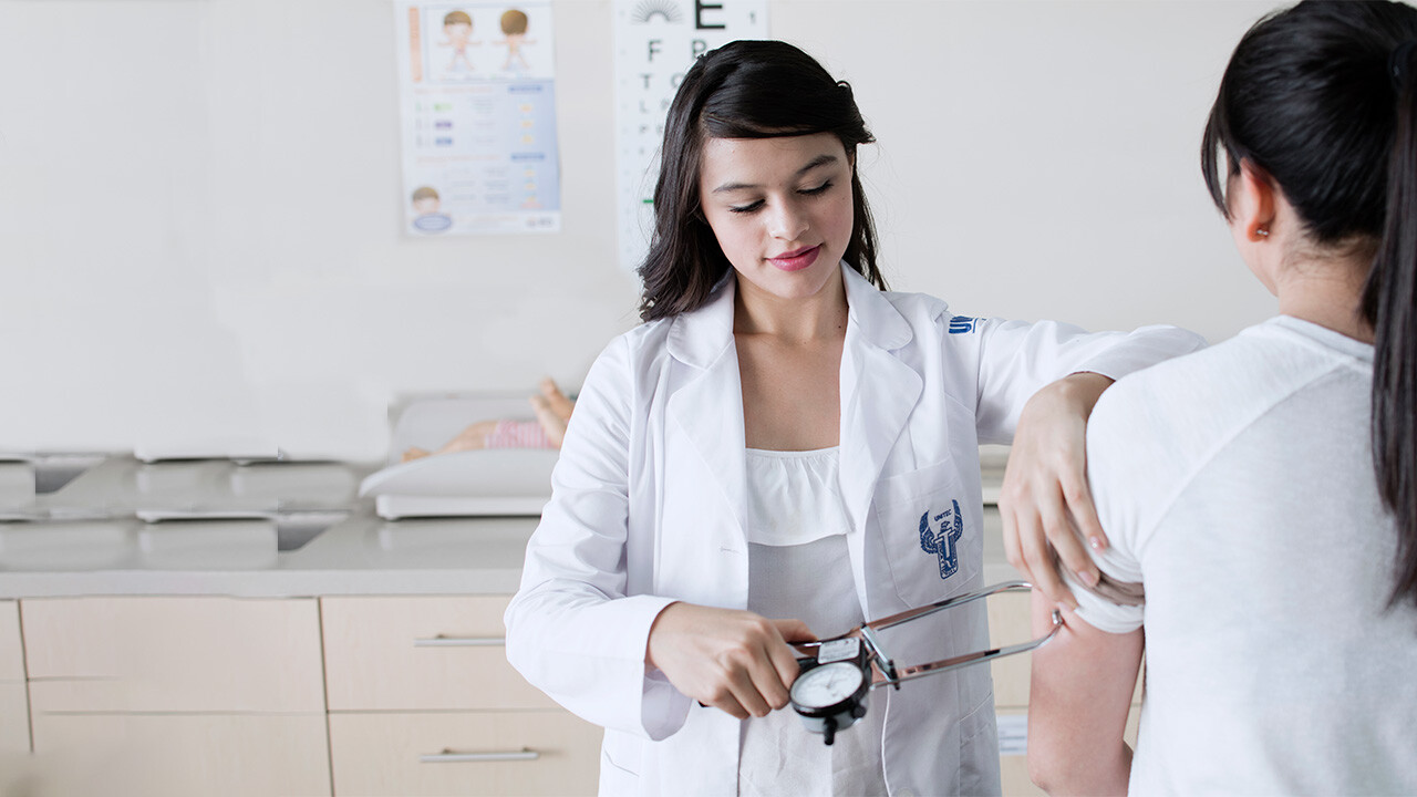 Una estudiante de la carrera en nutrición UNITEC practicando con paciente real midiendo el porcentaje de grasa corporal