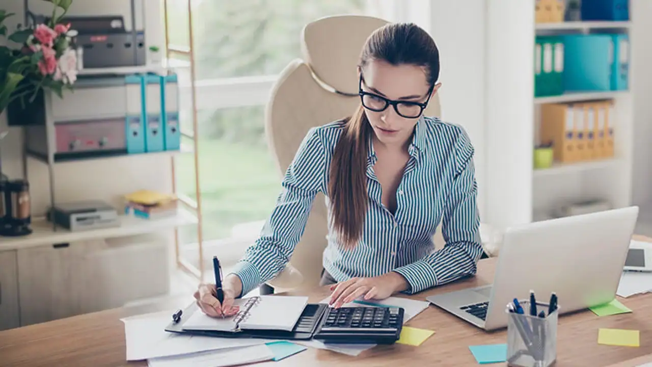 Profesional egresada de la carrera de contabilidad tomando apuntes durante su jornada laboral.