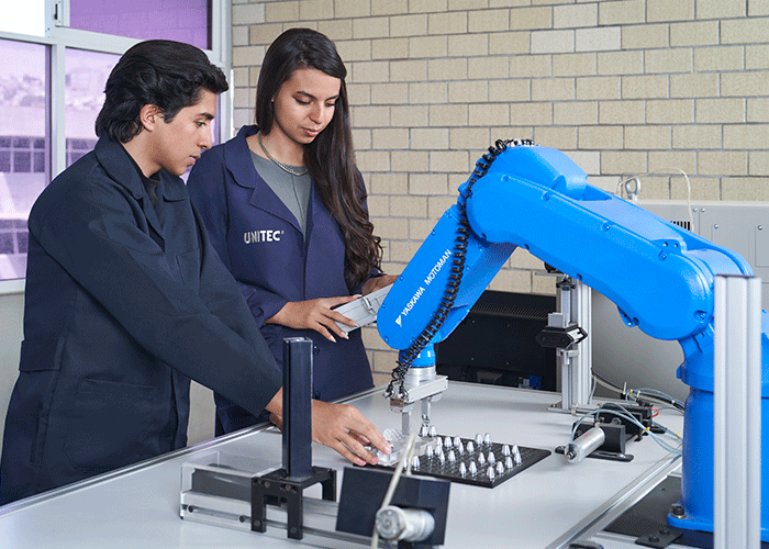 Alumnos de Ingeniería practicando con el brazo metálico en clase 