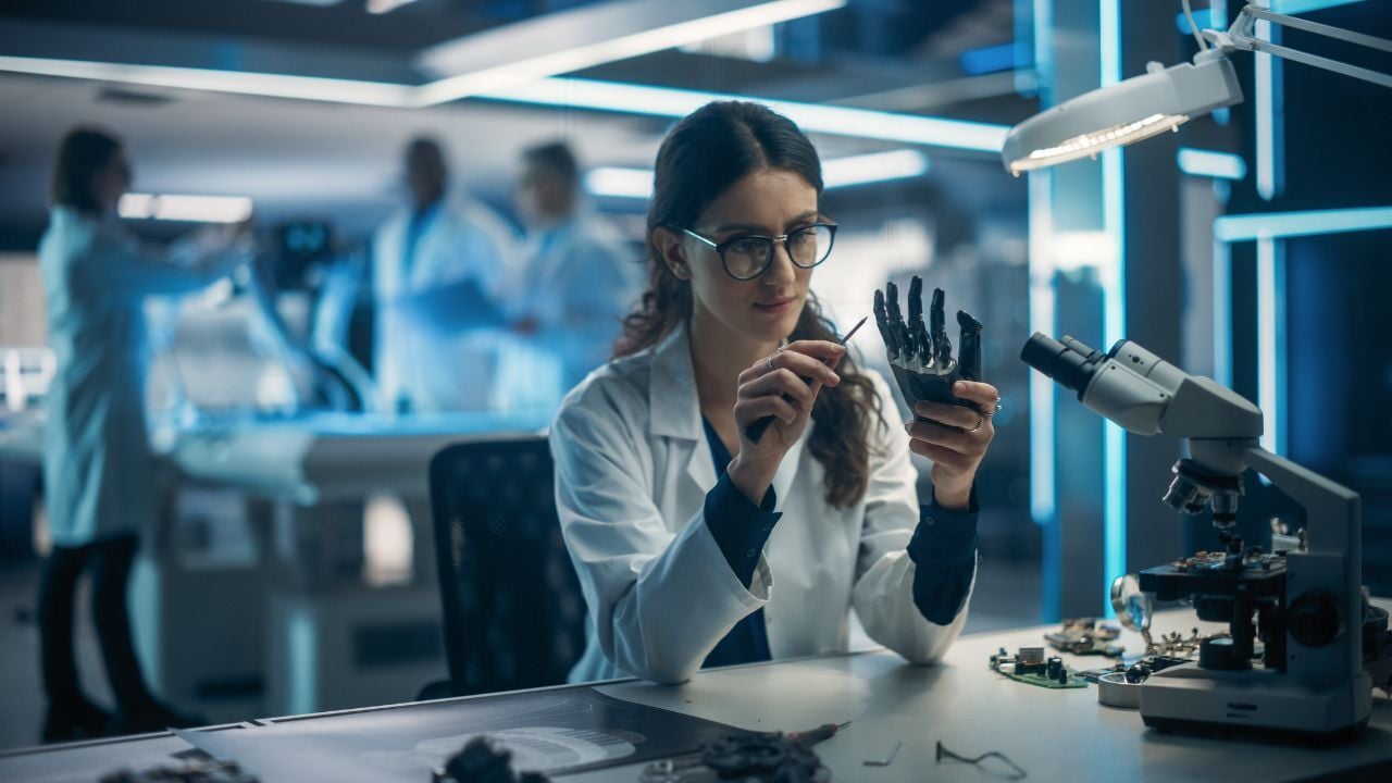 Alumna de la lic en biomedica, sosteniendo desarmador, realizando ajustes de una prótesis mecánica de mano