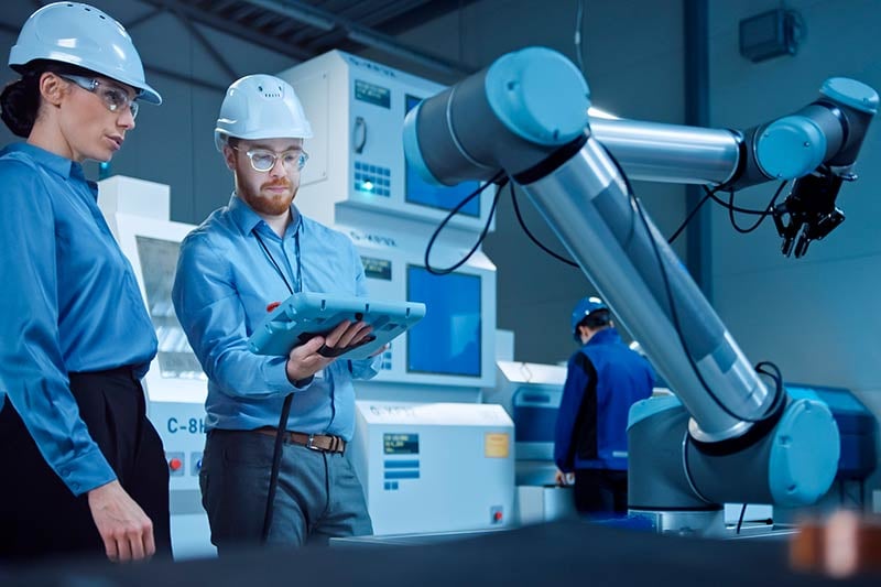 Ingenieros en manufactura manipulando un brazo mecánico