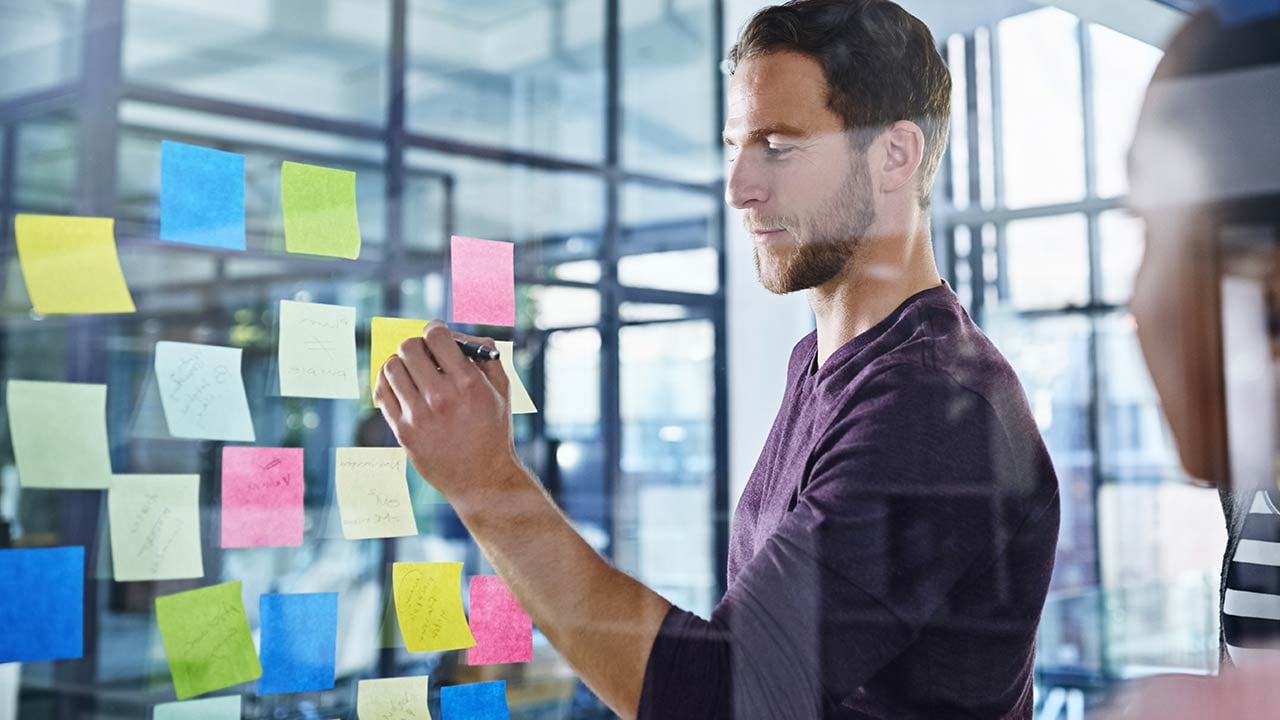 Alumno revisando pizarrón de ideas en oficina