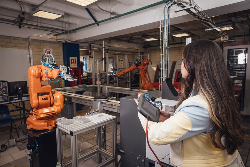 Laboratorio de manufactura UNITEC: alumna operando una celda robótica