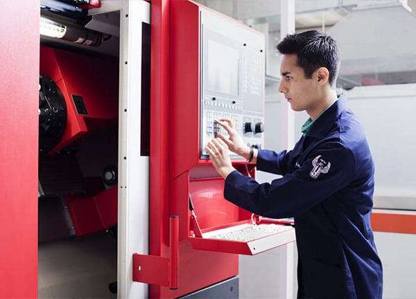 Laboratorio de máquinas y motores UNITEC: alumno operando un centro de maquinado CNC