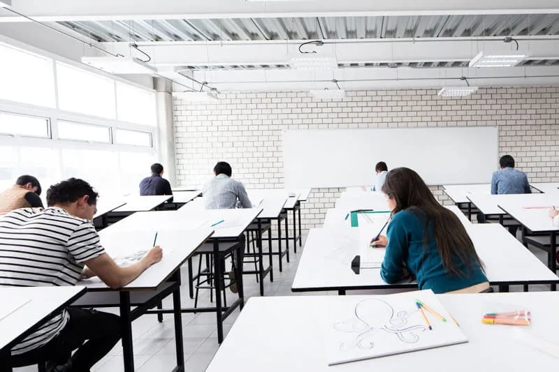 Jóvenes universitarios en un salón de clases, concentrados y estudianto su carrera de universidad.