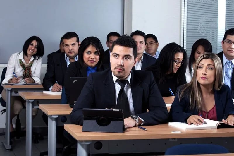 Adultos en un salón de clases poniendo atención a una clase de su licenciatura.
