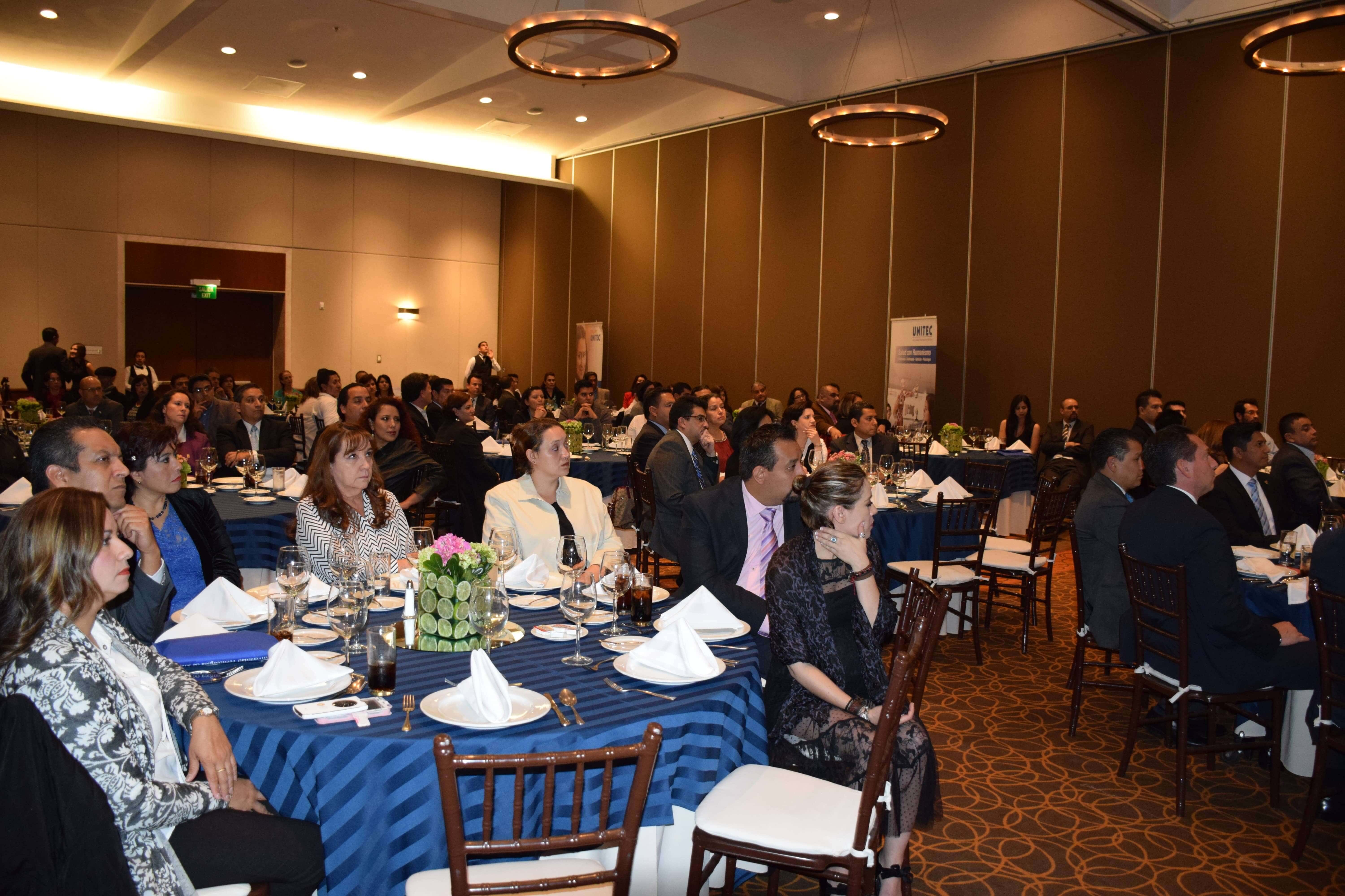 Evento UNITEC en salón de conferencias con asistentes atentos a la presentación