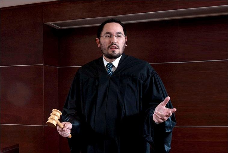 Juez en una sala de tribunal sosteniendo un mazo, representando la práctica de la justicia y el derecho.