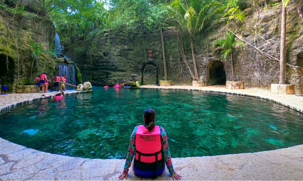 Vista de una alberca natural rodeada de vegetación en Xcaret, ideal para actividades de ecoturismo y relajación.
