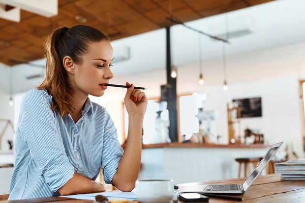 Mujer trabajando en su laptop en una cafetería moderna, reflejando productividad y flexibilidad laboral.