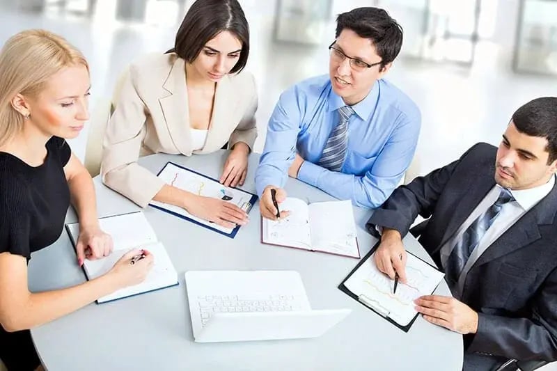 Cuatro profesionales de la carrera de comercio internacional en una junta empresarial.