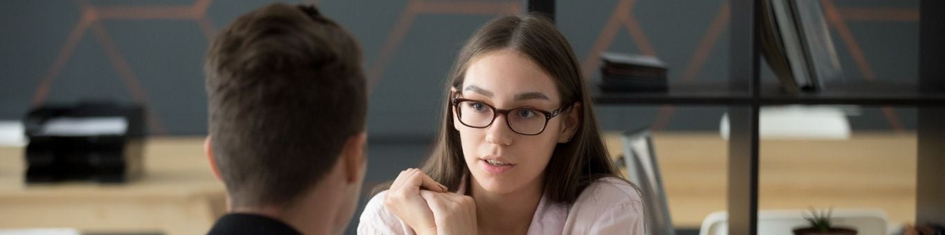 Joven profesional en entrevista de trabajo, destacando comunicación efectiva y confianza en un entorno laboral.