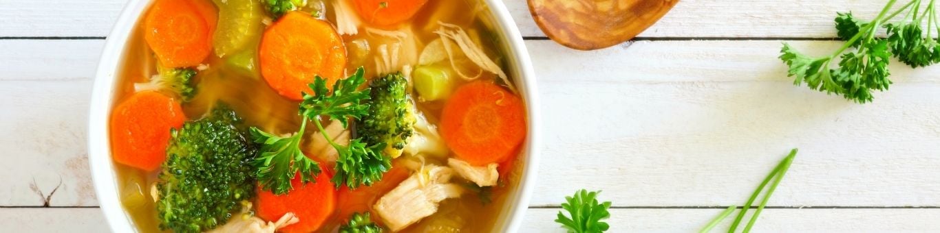 Plato de sopa con verduras frescas, como zanahorias y brócoli, destacando opciones saludables en la dieta diaria.