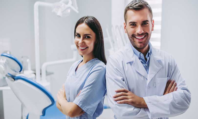 Odontólogo y asistente sonriendo